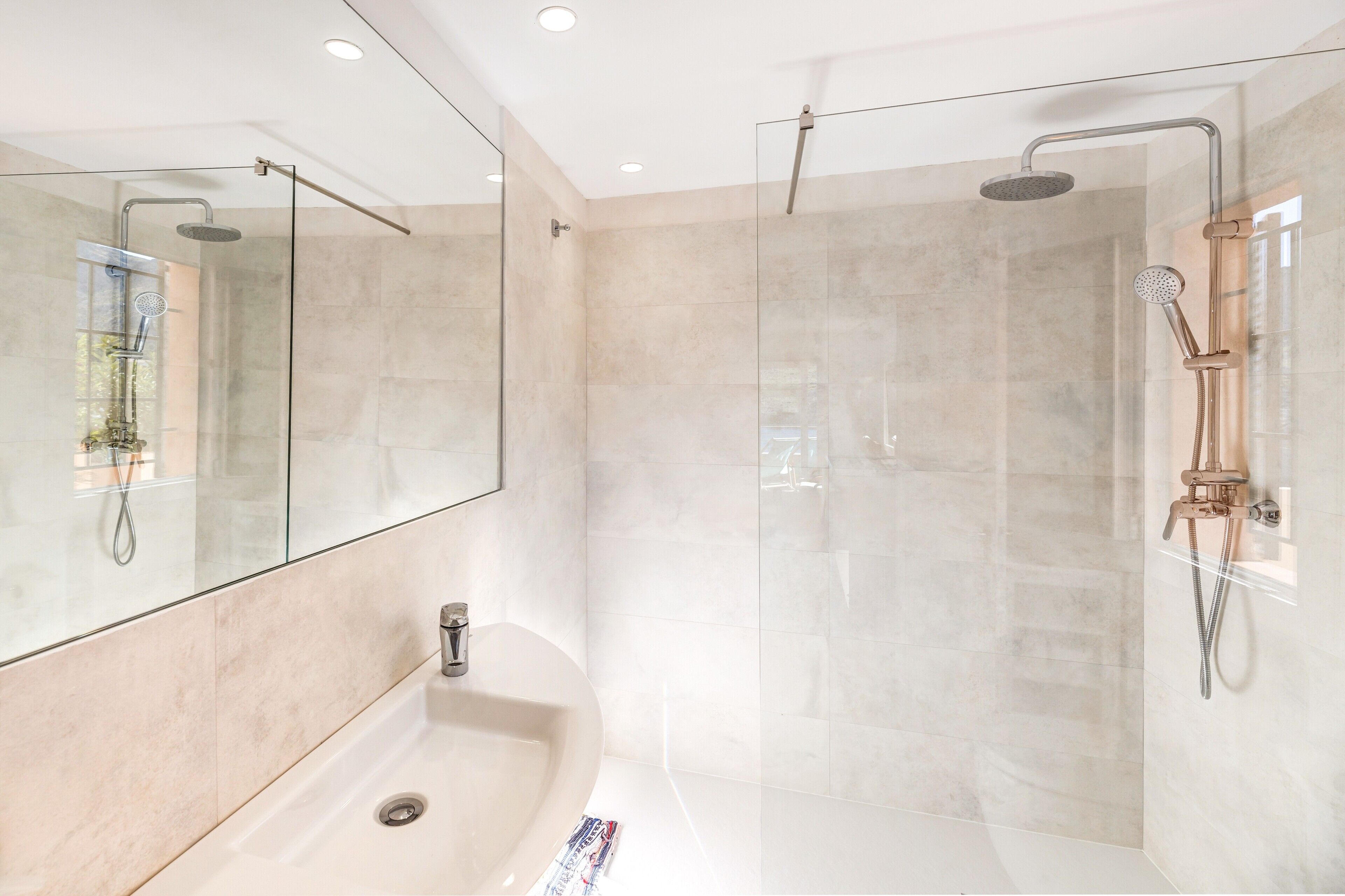 Une salle de bain moderne avec une douche à parois de verre, un lavabo et un grand miroir.