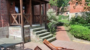A patio area with outdoor furniture, a brick building, and a garden path. - Apartment Alpha, haven of peace with complete facilities (Weenzen)