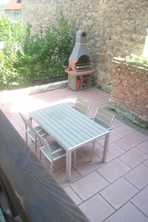 Eine Terrasse im Freien mit einer Steinmauer, einem Backofen aus Ziegeln und einem Tisch mit Stühlen.