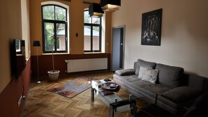 A living room with a sofa, a coffee table, a rug, a window, and a painting on the wall. - Apartment Alpha, haven of peace with complete facilities (Weenzen)