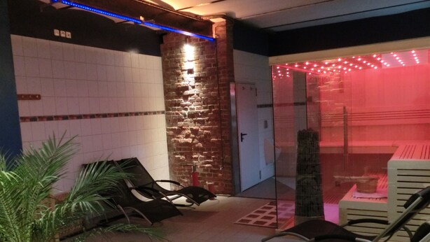A spa area with a brick wall, a glass door leading to a red-lit room, and several black lounge chairs. - Apartment Alpha, haven of peace with complete facilities (Weenzen)