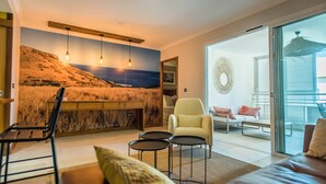 Ein modernes Wohnzimmer mit großem Fenster, einer Couch, einem Sessel und einem kleinen Tisch.