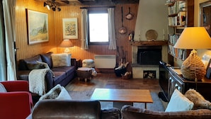 A cozy living room with a fireplace, wooden beams, a sofa, a coffee table, and a bookshelf. - Warm Traditional Chalet, Snow / Sun Hautes Alpes, All Comfort (Chabottes)