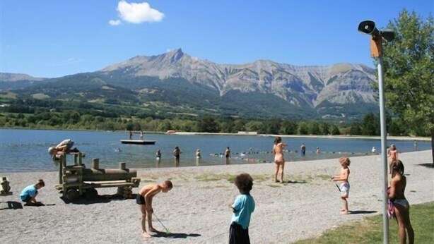 A beach with mountains in the background, a lifeguard tower, and people swimming and sunbathing. - Warm Traditional Chalet, Snow / Sun Hautes Alpes, All Comfort (Chabottes)