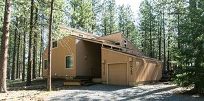 Une cabane en bois dotée d’un grand portail de garage, entourée de grands pins.