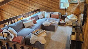 A cozy loft-style room with a large sectional sofa, a small round table, and a lamp.