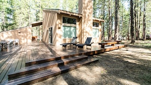A wooden deck with outdoor seating and a small building with large windows.