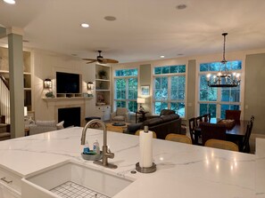 A modern kitchen with a marble countertop, built-in appliances, and a dining area with a large table and chairs.