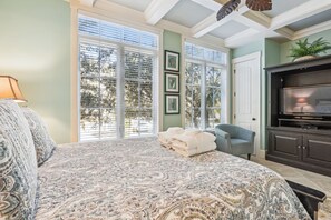 Un dormitorio con una cama grande, televisión y ventana con persianas.