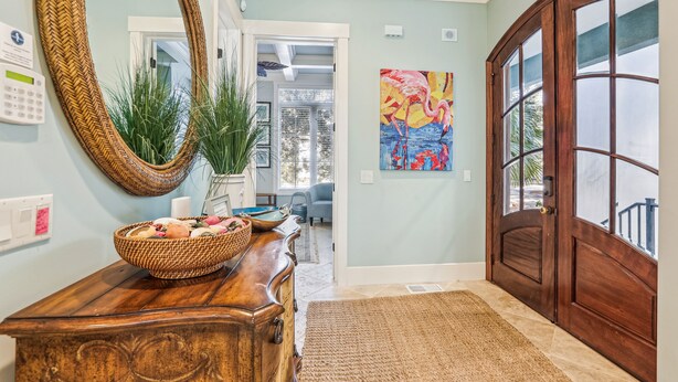 A hallway with a wooden dresser, a large mirror, a potted plant, a painting, and a wooden door. - 27 Corine Ln, Close to Beach, Free Golf, Pool, Beach Shuttle* (Hilton Head Island)