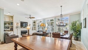 A spacious living room with a large wooden dining table, comfortable seating, a fireplace, and a television. - 27 Corine Ln, Close to Beach, Free Golf, Pool, Beach Shuttle* (Hilton Head Island)