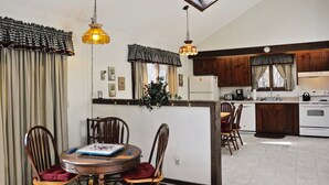 A kitchen with wooden cabinets, a dining table with chairs, and pendant lights.
