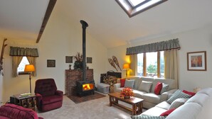A cozy living room with a fireplace, a sofa set, and a table with a vase of flowers.