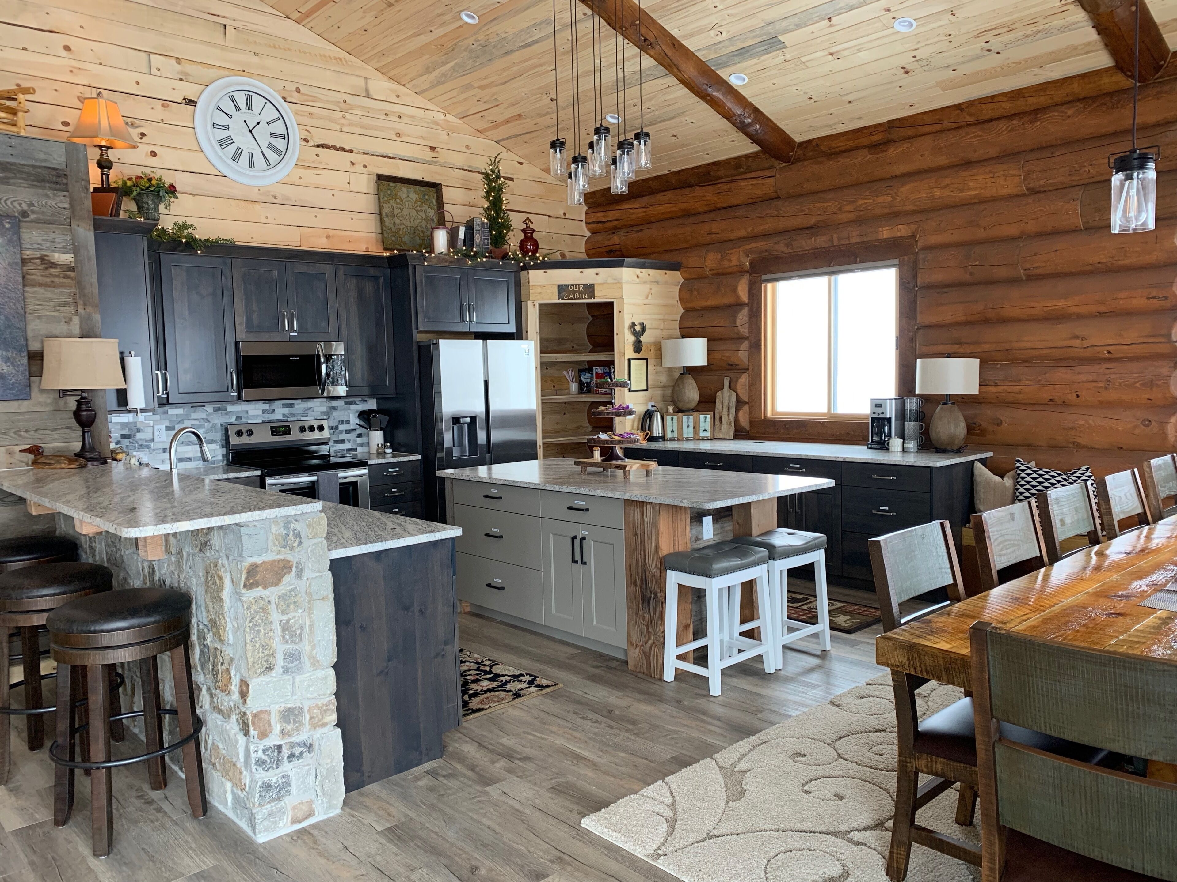 A spacious kitchen with dark cabinets, a large island, and a rustic wooden ceiling.