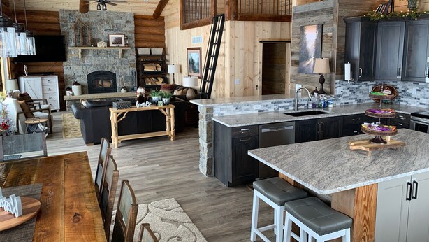 Une cuisine spacieuse dotée d’une cheminée en pierre, de poutres apparentes et d’un îlot central moderne avec des tabourets de bar.