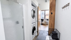 A laundry room with two washing machines, a drying rack, and a tiled floor.