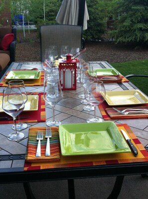 Una mesa para comer al aire libre con platos, vasos, cubiertos y un farol.