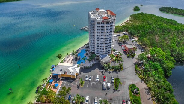 Un hotel di grandi dimensioni con piscina e area parcheggio, immerso nell'acqua e nel verde.