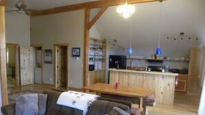 Una sala de estar acogedora con un sofá, una mesa de comedor de madera y una zona de cocina con armarios y electrodomésticos de madera.