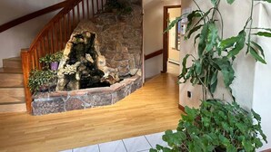 Un escalier avec un mur en pierre et une rampe en bois, menant à un deuxième étage.