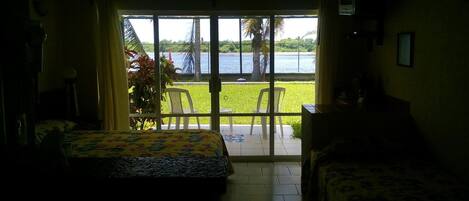 Una habitación con dos camas, vistas a un cuerpo de agua y un balcón con sillas y una mesa.