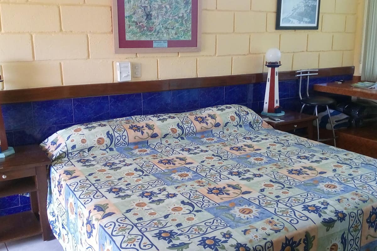 Una habitación de hotel con una cama, dos mesitas de noche, un escritorio y una silla.