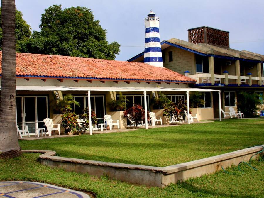 A hotel with a covered outdoor seating area, a lighthouse, and a pool.