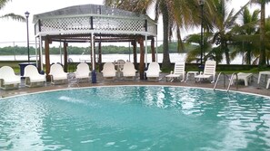 Una piscina con sillas de descanso y un pabellón.