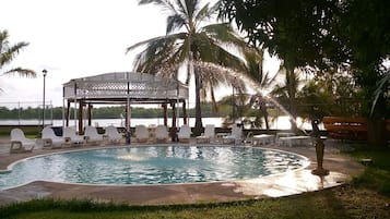 Una piscina al aire libre, sombrillas, sillones reclinables de piscina