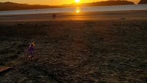 A beach at sunset with a clear sky, calm sea, and distant hills. - Beautiful Condominium - Wifi access throughout and 300 Yards from the Beach! (Samara)
