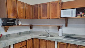 A kitchen with wooden cabinets, a microwave, a toaster, and a marble countertop. - Beautiful Condominium - Wifi access throughout and 300 Yards from the Beach! (Samara)
