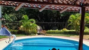 A swimming pool with a swan, surrounded by greenery and a covered patio area. - Beautiful Condominium - Wifi access throughout and 300 Yards from the Beach! (Samara)