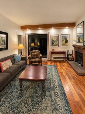 A living room with a sofa, armchair, coffee table, fireplace, and artwork on the walls. - Highest Rated, Lowest Rates in Snow Blaze: 2/2, A/C, Pool, Hot Tub, Gym, Firepit (Park City)