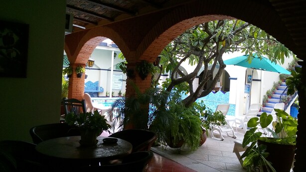 An indoor patio area with brick arches, potted plants, and outdoor seating. - Hotel Posada del Rey (San Blas)