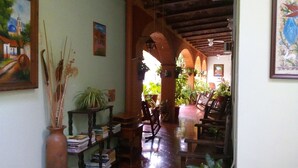 A cozy interior with a wooden floor, bookshelves, and potted plants. - Hotel Posada del Rey (San Blas)