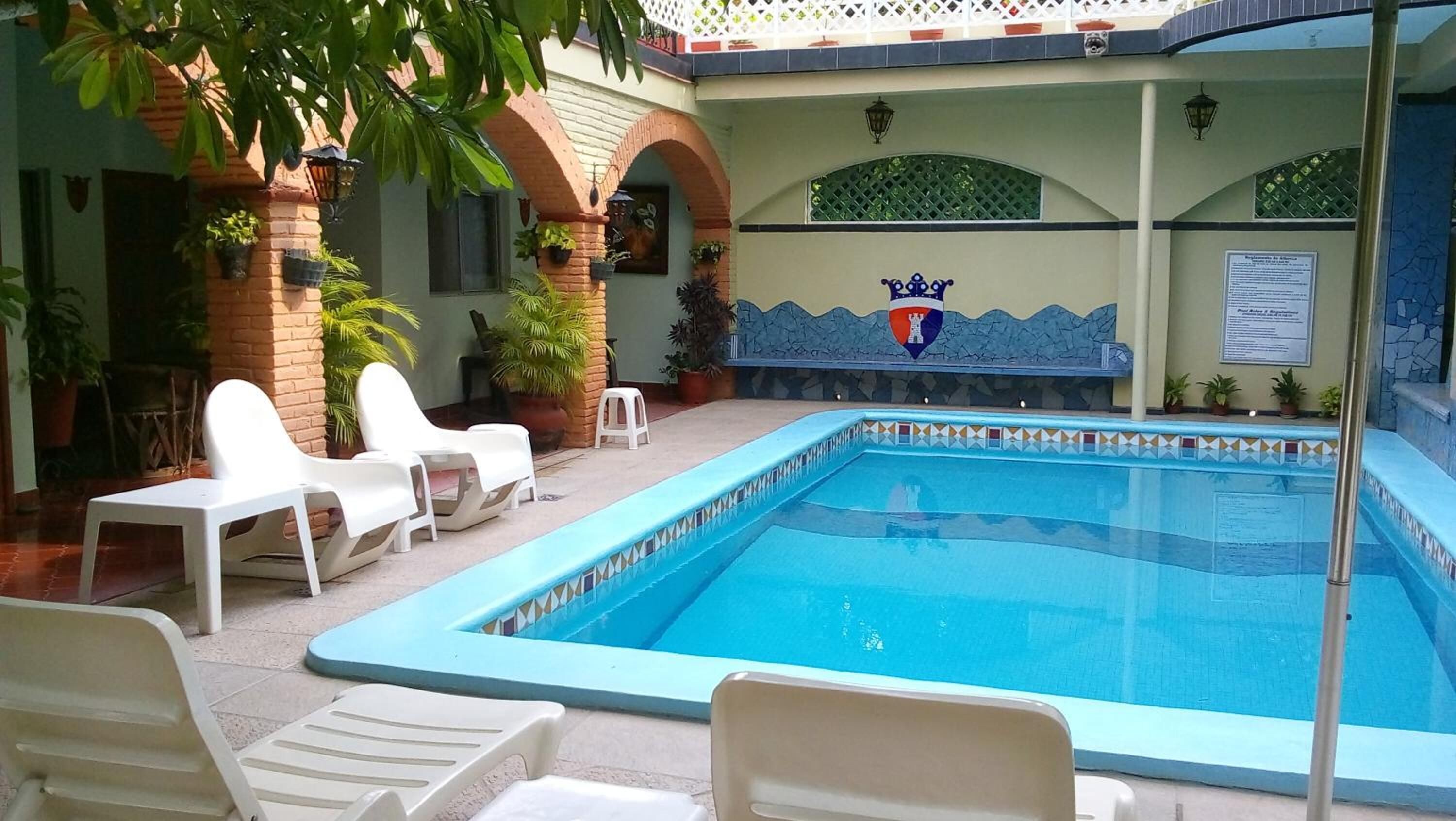 A swimming pool with a tiled border and a decorative crest on the wall.