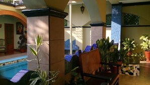 A pool area with lounge chairs, potted plants, and a tiled floor. - Hotel Posada del Rey (San Blas)