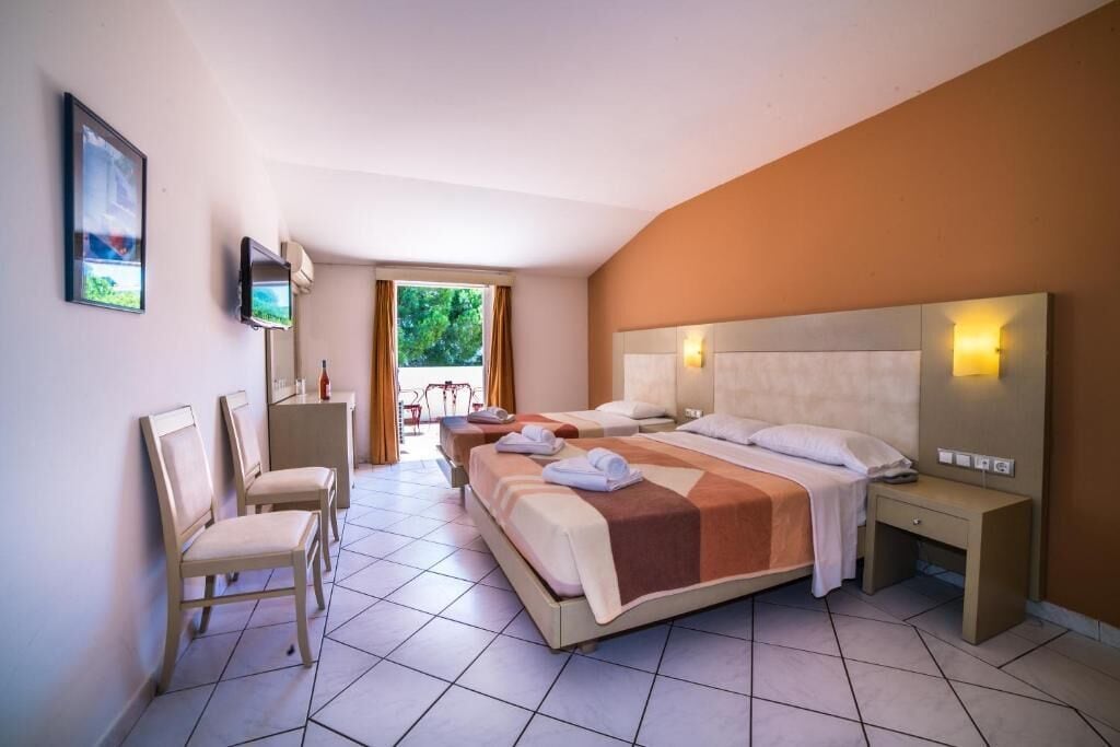 A hotel room with a large bed, two bedside tables, a TV, and a chair.