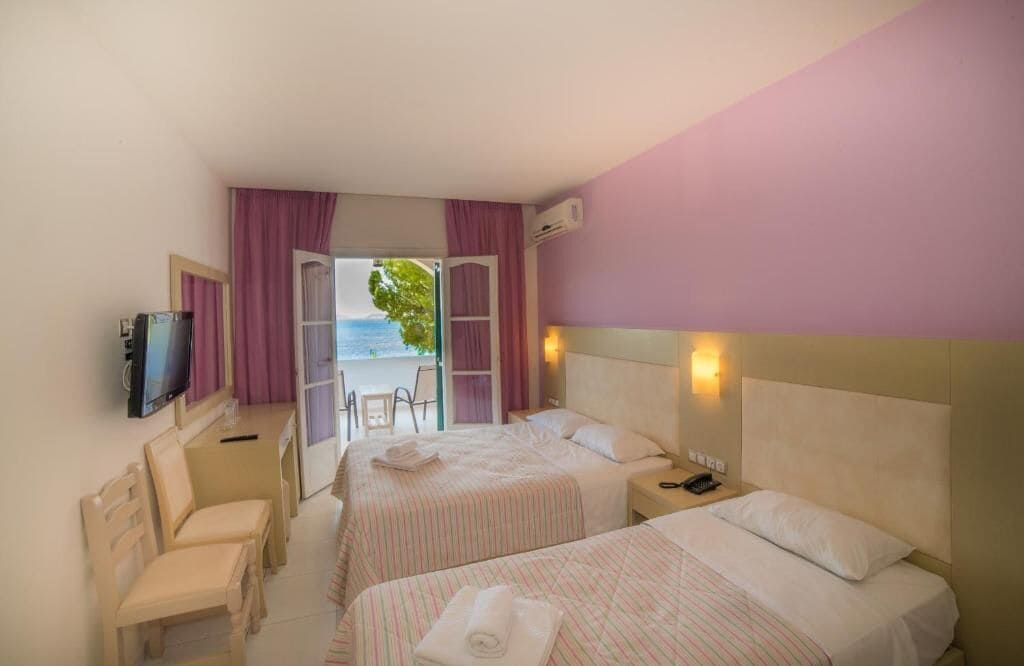 A hotel room with two beds, a TV, a desk, and a chair.