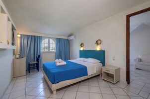 Una camera da letto con un letto, una scrivania, una sedia, un comodino e una finestra con tende.