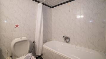 A bathroom with a toilet, a shower curtain, and a bathtub.