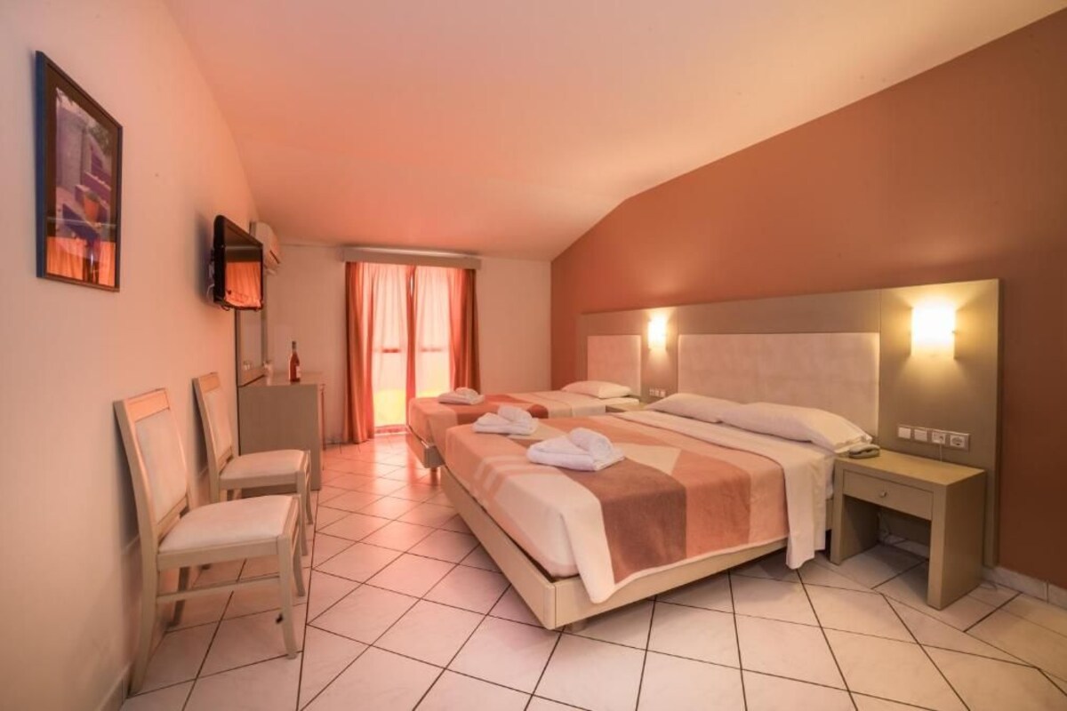 A hotel room with a large bed, two bedside tables, a chair, a desk, and a window with curtains.