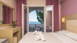 A hotel room with a bed, a desk, a chair, and a view of the sea. - Porto Koukla Beach Hotel (Zakynthos)