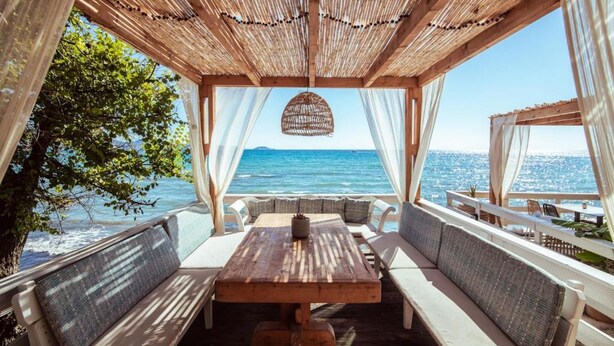 A wooden deck with a table and benches, overlooking a body of water. - Porto Koukla Beach Hotel (Zakynthos)