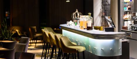 A bar area with a counter, stools, and a shelf with bottles.