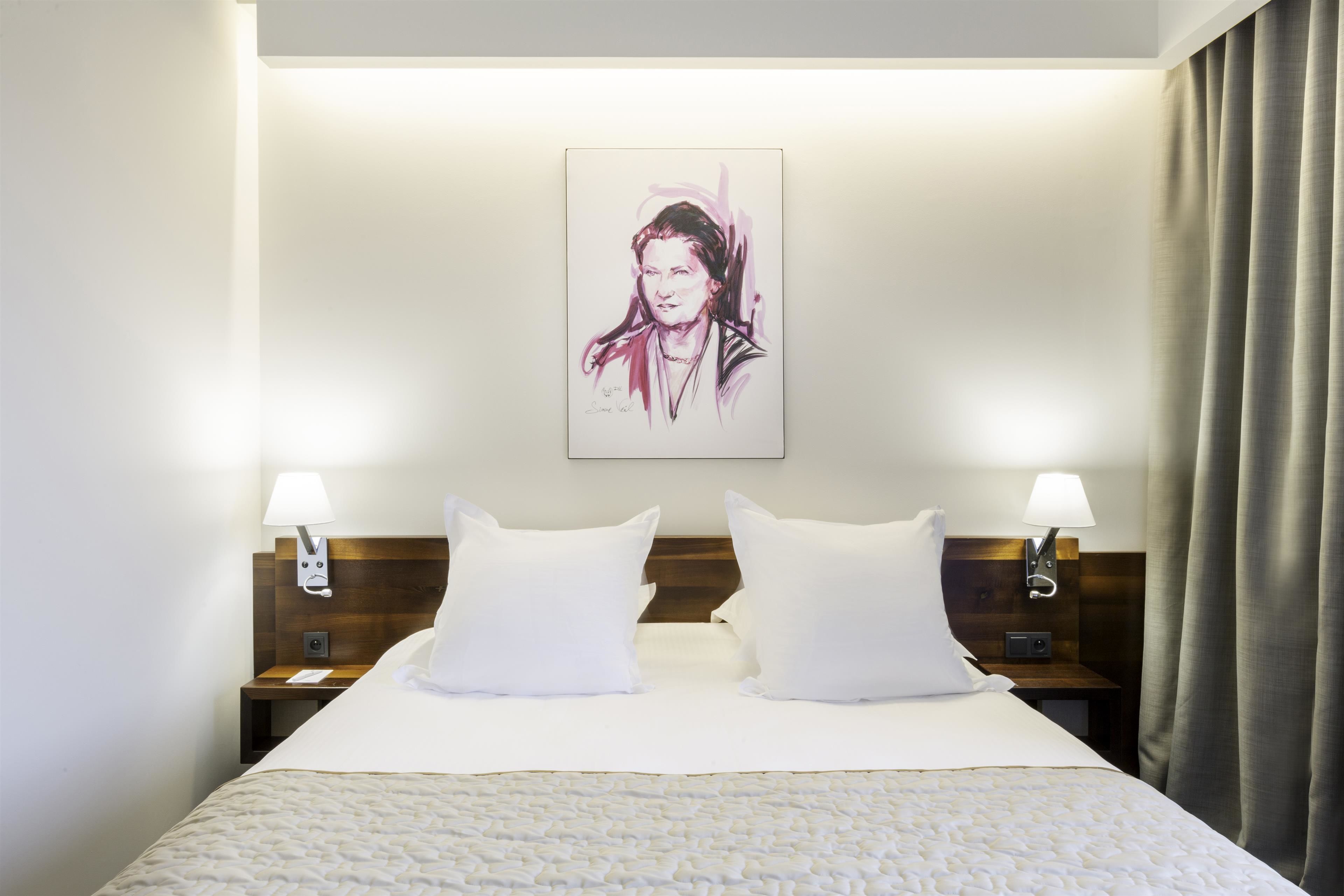 A hotel room with a large bed, two bedside tables with lamps, a headboard, and a framed artwork on the wall.