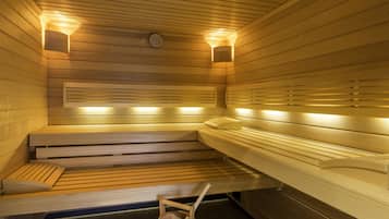 Una sauna con bancos de madera, un cubo de madera e iluminación en la pared.