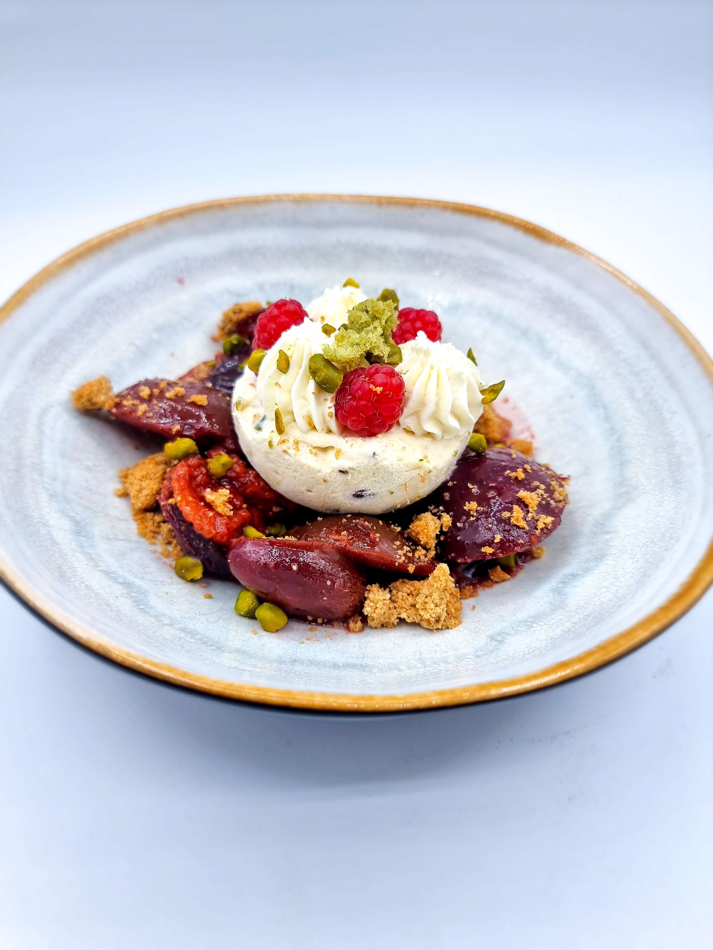 Un postre en un plato con detalles dorados y blancos.