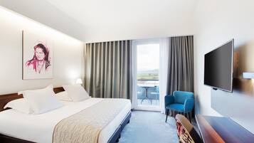 Une chambre d’hôtel comprenant un lit, un téléviseur à écran plat, une chaise et un balcon avec une table et des chaises.