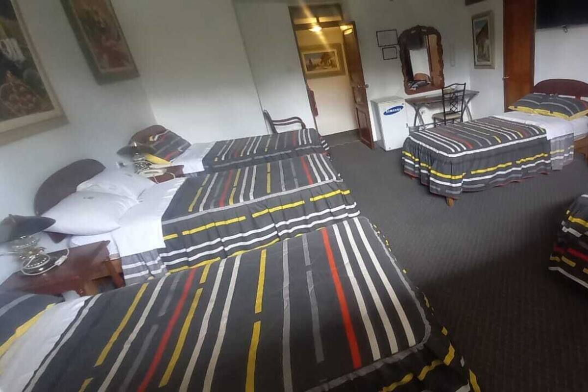 Ett hotellrum med två separata sängar, ett skrivbord, en stol och ett litet bord.